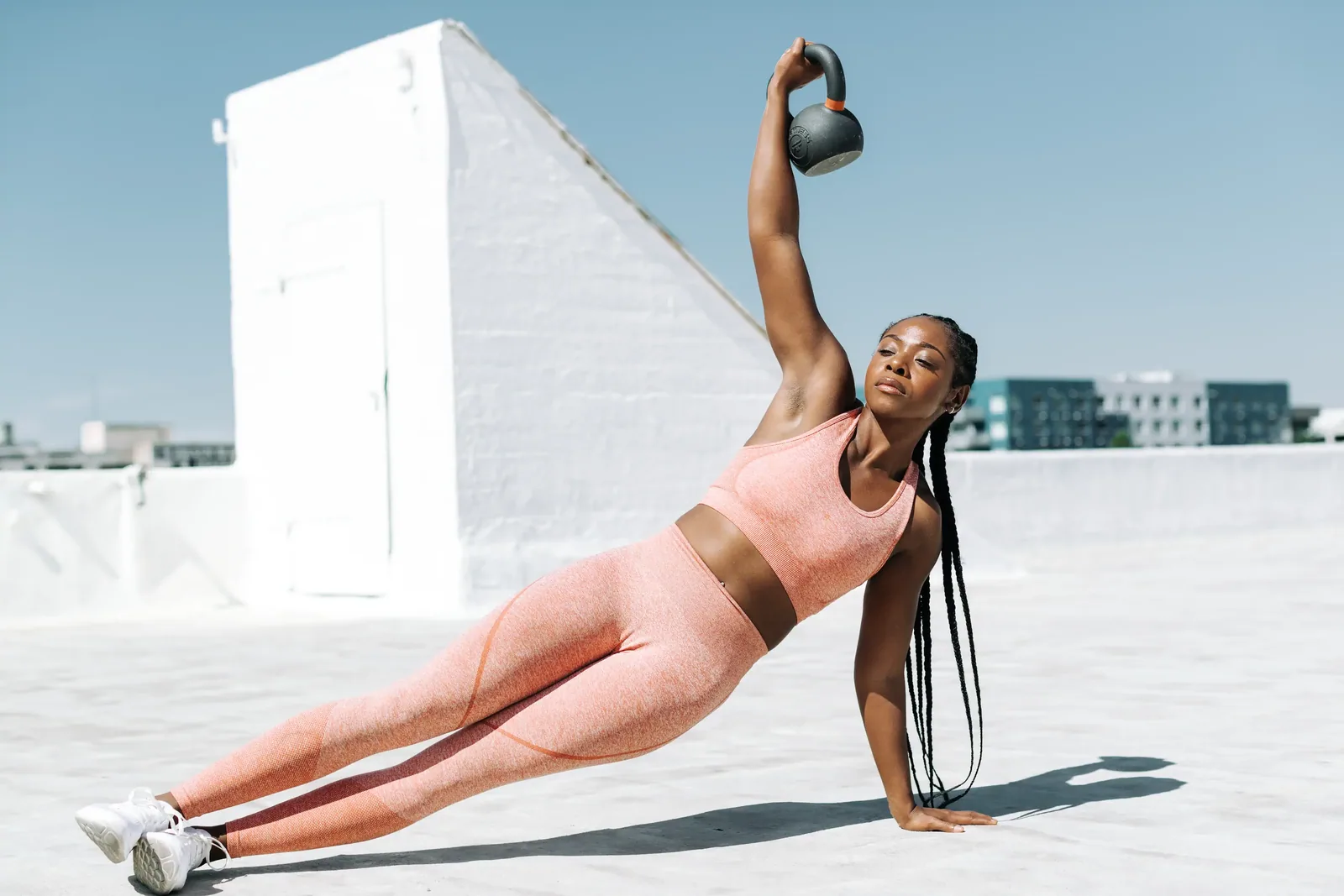 Vic holding a side plank with a kettlebell overhead